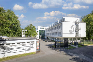 Das Foto zeigt eine Frontansicht des Gebäudes am Standort ISAS City. Die Fassade ziert ein Mikroskop.