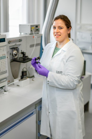 Luisa Speicher at the mass spectrometer. She is holding a sample mount in her hand.