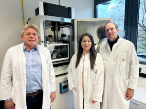 The two corresponding authors Dr Reinhard Viga (left) from UDE and Prof Dr Matthias Gunzer (UDE / ISAS) are standing in front of the ComplexEye microscope with one of the two first authors, PhD student Zülal Cibir.