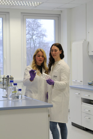 Darleen Hüser und Flora Weber stehen gemeinsam im Labor und besprechen ihre Ergebnisse. Darleen Hüser and Flora Weber stand together in the lab and discuss their results.