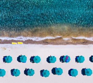 Das Foto zeigt einen Strand mit blauen Sonnenschirmen.