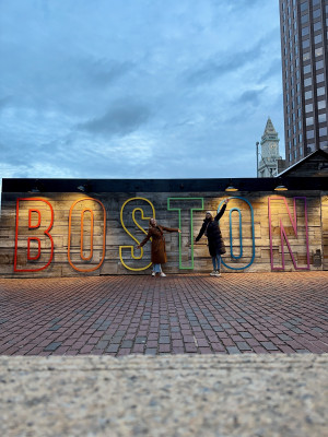 Darleen Hüser und Flora Weber posieren vor einen großen “BOSTON“-Schild. Darleen Hüser and FLora Weber pose in front of a large “BOSTON“ sign.