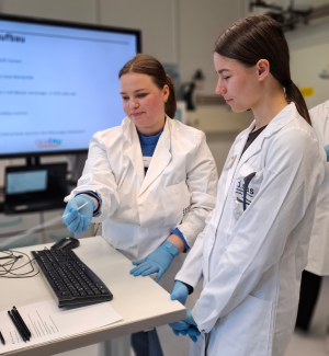 Doktorandin Annika Fechner reicht Helene das Mundstück für die Atemluftmessung am Ionenmobilitätsspektrometer.